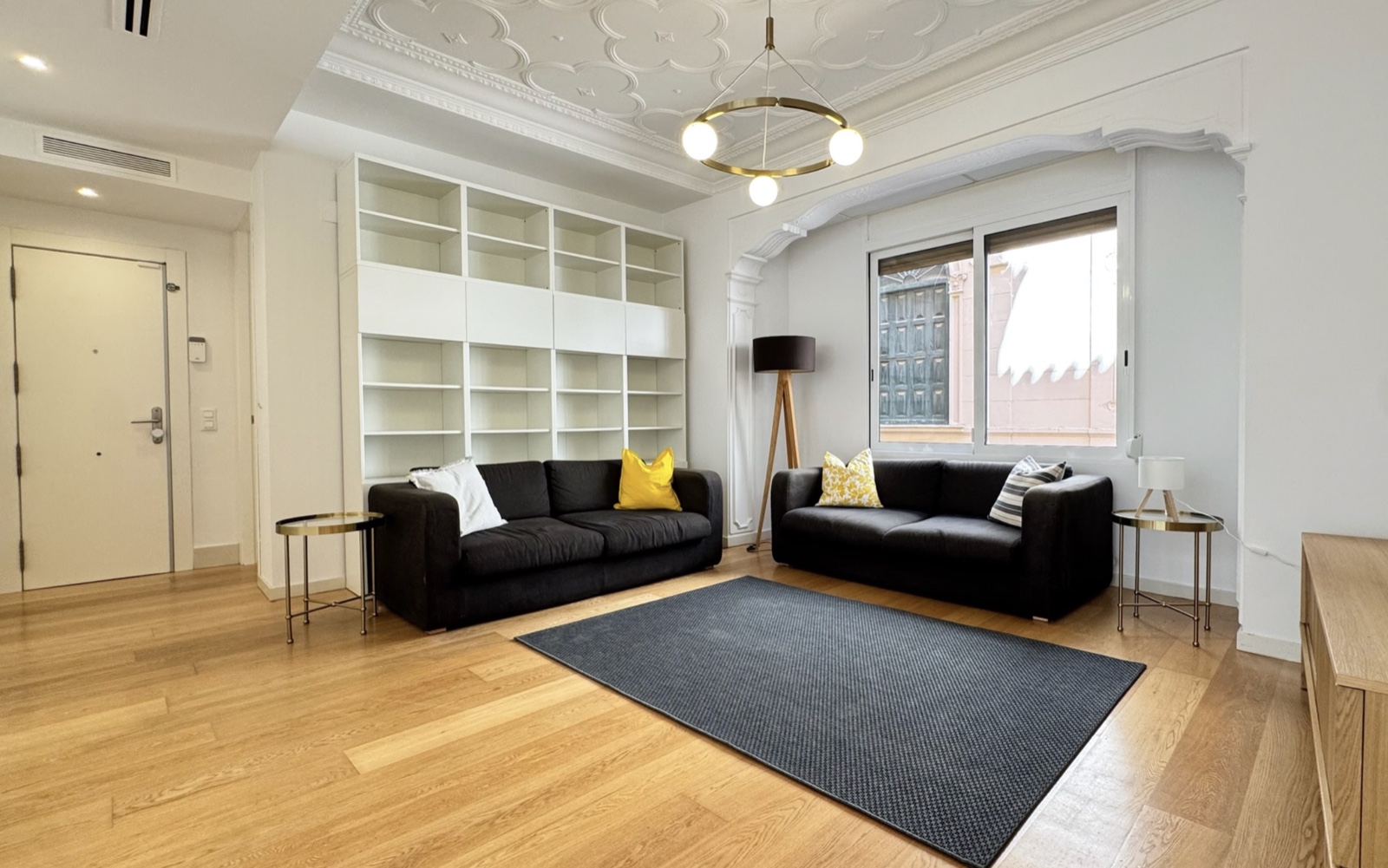 Salón del piso amueblado en Ciutat Vella · dos sofás, biblioteca empotrada, parquet, techos con escayola